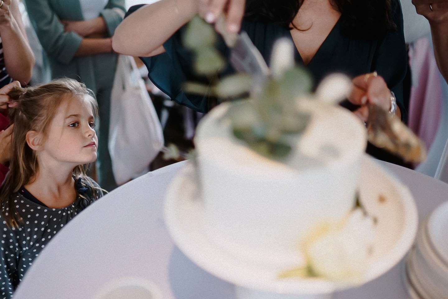 Kind schaut sich ein Stück der Hochzeitstorte an