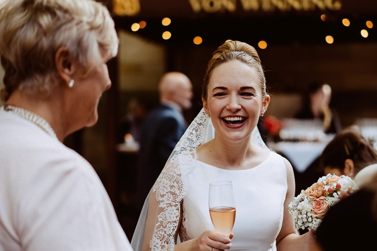 lachende Braut beim Sektempfang im Weingut von Winning Deidesheim nach der Hochzeit