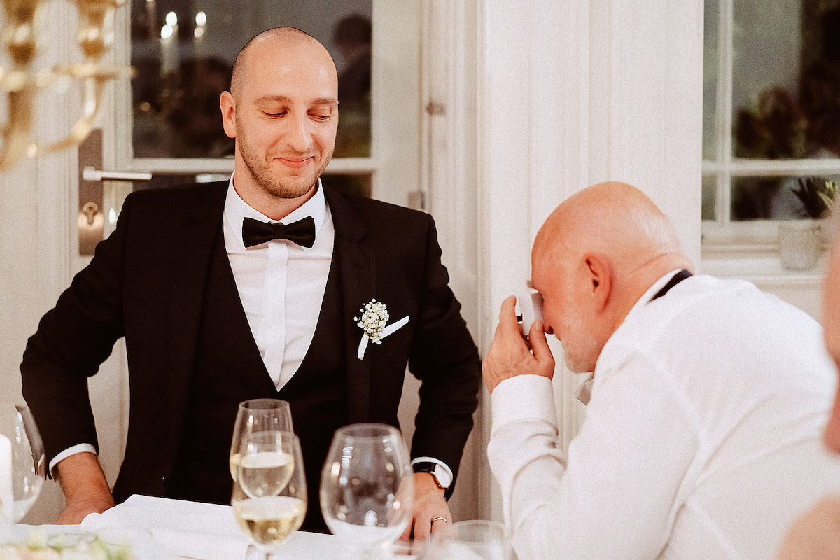 Vater des Bräutigams fotografiert seinen Sohn mit einer Einwegkamera bei dessen Hochzeit
